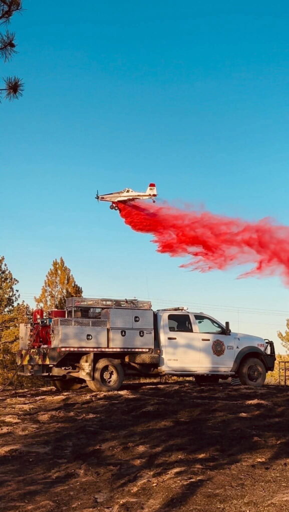 Air tanker dropping retardant above a brush truck